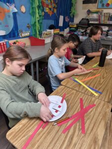 Sudents making baskets from paper plates and construction paper