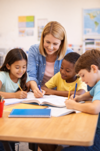 Female tutor working with three elementary school students around a table